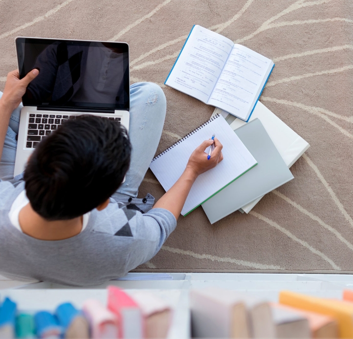 Student sitting on the floor, studying on a laptop
